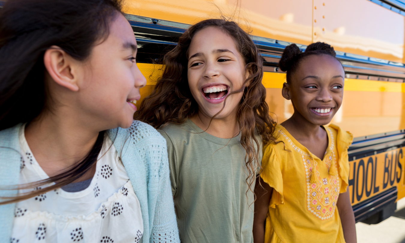 Group of diverse middle school kids by school bus